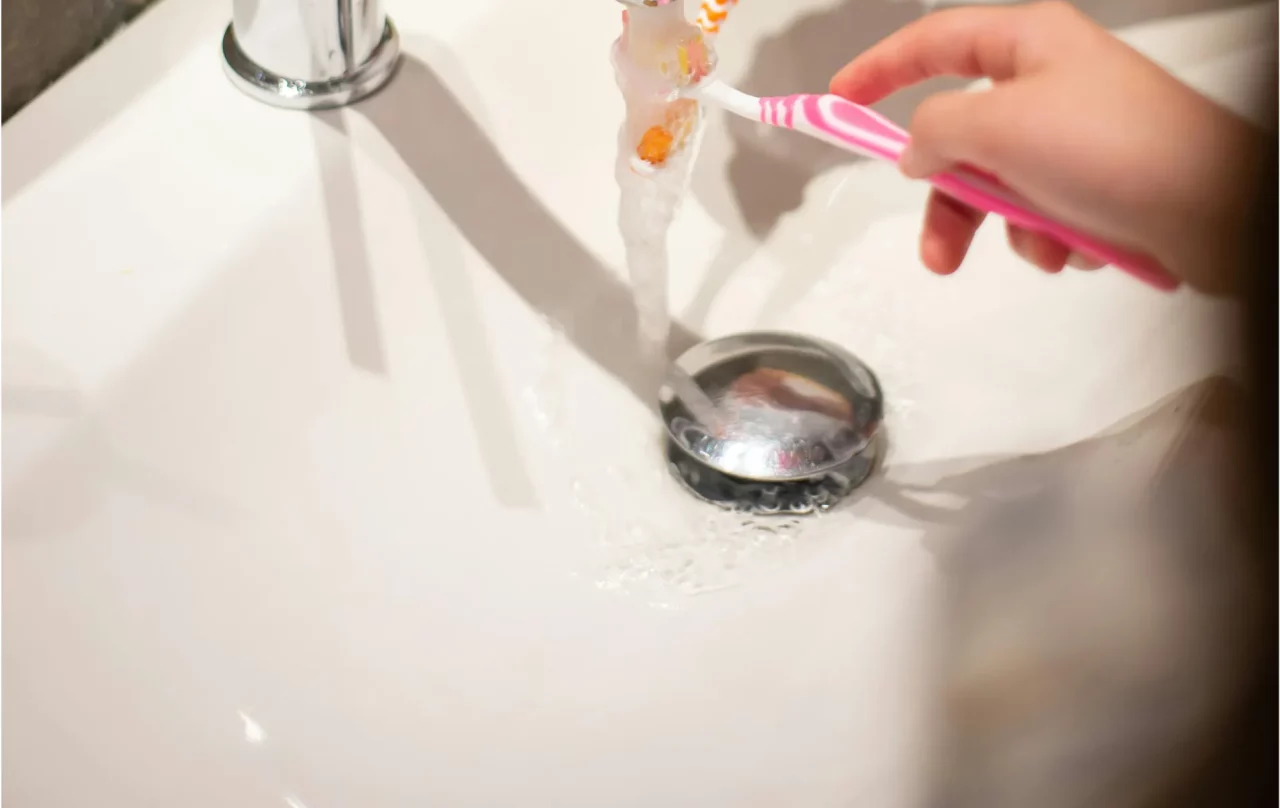 Vue sur la bonde de lavabo pendant qu'une personne se brosse les dents.