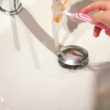 Vue sur la bonde de lavabo pendant qu'une personne se brosse les dents.